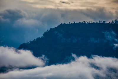 Low angle view of mountains seen through cloud against sky