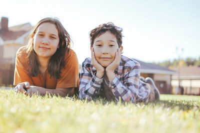 Portrait of smiling siblings lying on grass