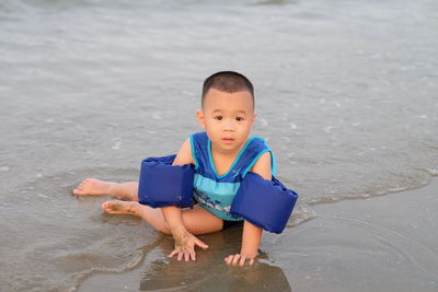 Boy sitting on shore at beach