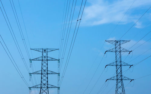 Low angle view of electricity pylon against blue sky