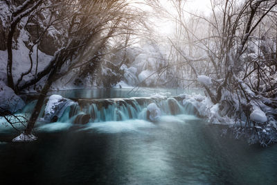 Scenic view of waterfall in forest during winter