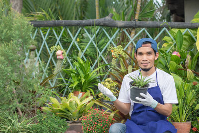 Portrait of a smiling young man holding flowering plants