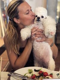 Woman kissing dog in restaurant
