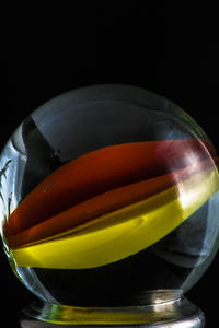 Close-up of multi colored glass on table against black background