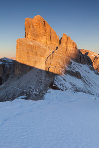 Rock formation on snow covered land against sky