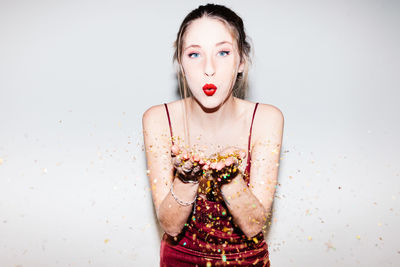 Portrait of young woman wearing mask against white background