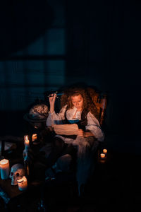 Woman sitting in illuminated room