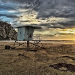 Lifeguard hut on beach against cloudy sky