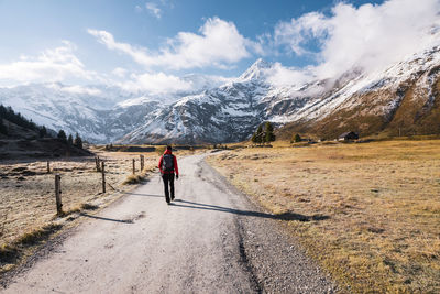 Woman walking on footpath amidst fall colored highland and snow capped mountains in gastein, austria