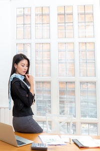 Side view of young woman using mobile phone at home