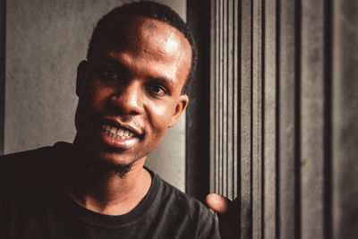 Close-up portrait of smiling man against wall