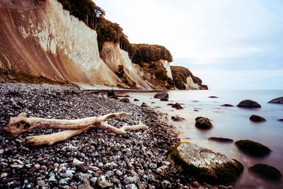 Rocks on shore at beach against sky