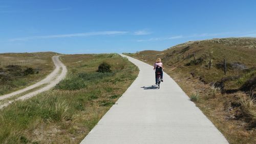 Man riding bicycle on road against sky