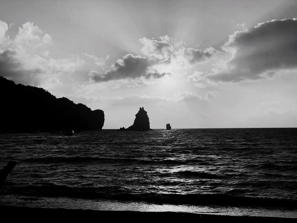 SILHOUETTE ROCKS ON SHORE AGAINST SKY