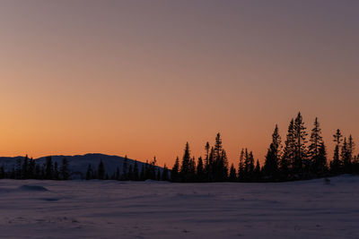 Snow covered landscape against sky during sunset