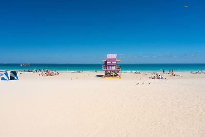 People near of one of the famous and colorful beach guard cabins on miami beach during a sunny day