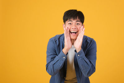 Portrait of smiling young woman against yellow background