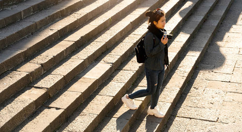 High angle view of woman on steps with camera during day