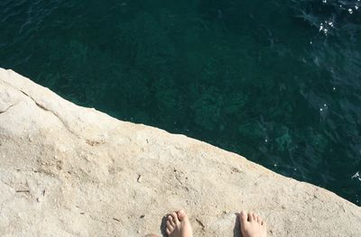 Low section of person on rock by lake