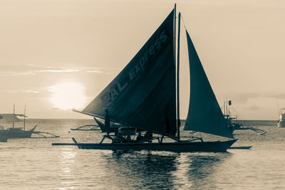 Sailboat sailing on sea against sky during sunset