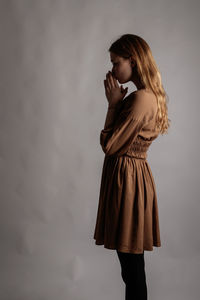 Woman looking away while standing against wall