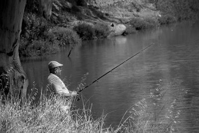 Rear view of man fishing in lake