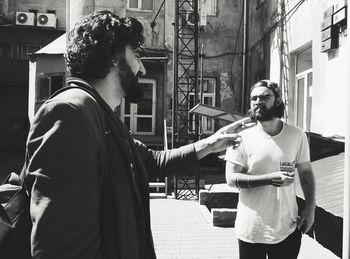 Men smoking cigarette while standing against building