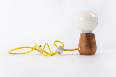 Close-up of light bulb on table against white background