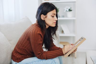 Young woman using mobile phone while sitting on sofa at home