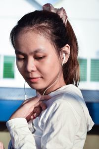 Side view of young woman listening music through headphones