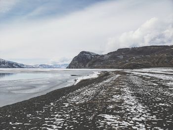 Scenic view of snowcapped mountains by sea against sky