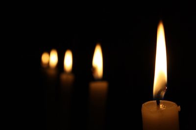 Close-up of lit candles in darkroom