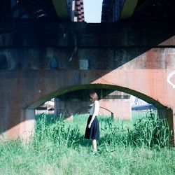 Side view of woman standing under bridge