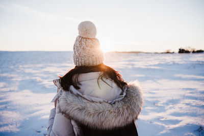 Rear view of woman looking at snow covered land against sky