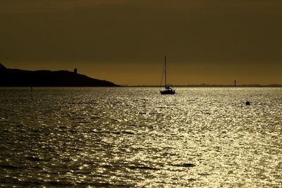 Boat sailing in sea at sunset