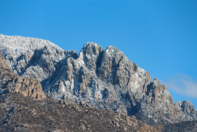 Low angle view of rocky mountains against clear blue sky