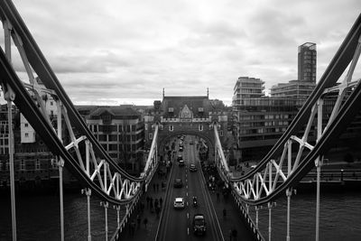 Bridge over river in city against cloudy sky