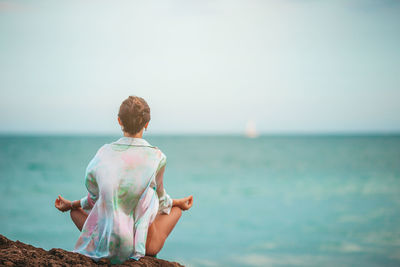 Rear view of woman standing at beach against clear sky