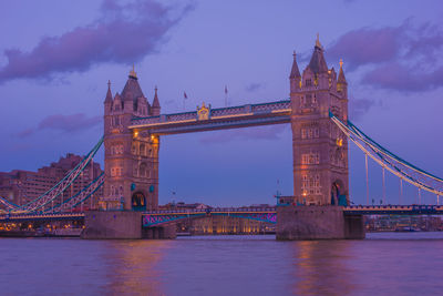 Low angle view of tower bridge over thames river against purple sky at dusk