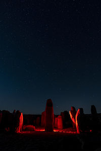 People on rock formations against sky at night