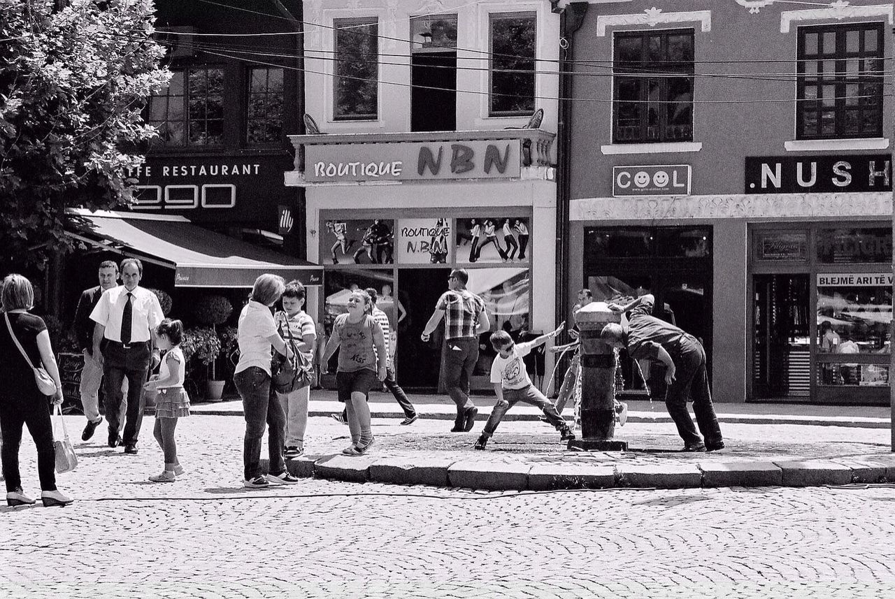 building exterior, men, architecture, built structure, person, city, walking, text, lifestyles, street, city life, large group of people, full length, western script, communication, leisure activity, building, day, outdoors