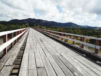 Boardwalk leading towards mountain against sky