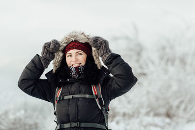 Smiling woman wearing warm clothing while standing on mountain during winter