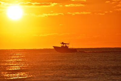 Silhouette sailboat in sea against sky during sunset