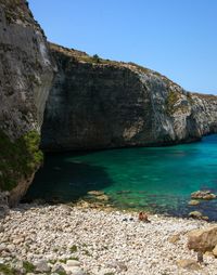 Rock formations by sea against clear sky