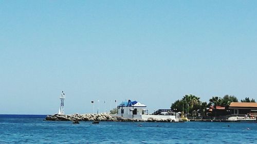 Boats in sea against clear blue sky