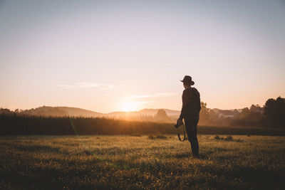 Rear view photographer standing on field during sunrise