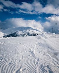 Scenic view of snow covered land against cloudy sky