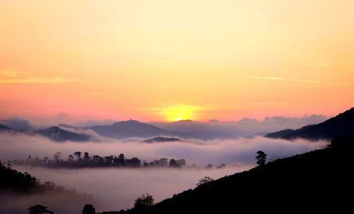 Scenic view of silhouette mountains against orange sky