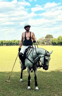 Man riding horse on field against sky, polo